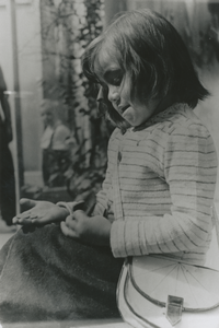 876873 Portret van een onbekend meisje met een schoudertasje zittend bij een winkel in Wijk C te Utrecht, waar ze haar ...